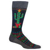A single crew sock with a dark navy background featuring a green cactus wearing a red pot and yellow star, surrounded by festive red and green geometric patterns on the leg and foot, with a solid dark gray cuff, heel, and toe.