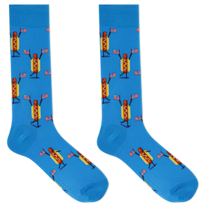 A pair of bright blue crew socks featuring a repeating cartoon hot dog character holding small American flags, shown on a plain white background.