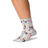 A pair of light gray crew socks with a colorful cartoon pattern of sewing machines, shown on a model's feet against a white background.