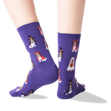 A pair of purple crew socks with a repeating pattern of dogs dressed in Halloween costumes, shown on a person's feet against a clean white background. thumbnail