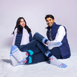 Two people sitting on a snowy surface wearing matching blue and gray socks. thumbnail
