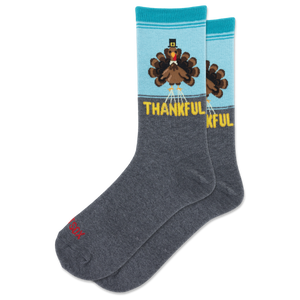 A pair of crew socks with a Thanksgiving theme. The lower half is dark heather gray, while the upper half is light blue and features a cartoon turkey wearing a black top hat with a red band, above the word 'THANKFUL' in yellow.