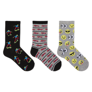 Three pairs of novelty crew socks displayed side-by-side on a plain white background. The left pair is black with colorful cartoon skateboarder prints.