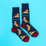 A pair of navy blue crew socks with a repeating pattern of a golden retriever dog holding a cocktail glass and the text 'hard licker', with red heels and toes, displayed on a bright cyan background. thumbnail