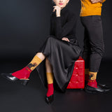Person wearing black dress and red shoes with a black background