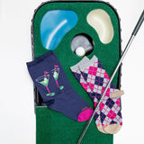 Two pairs of socks with golf-themed designs on a green golf simulator mat.