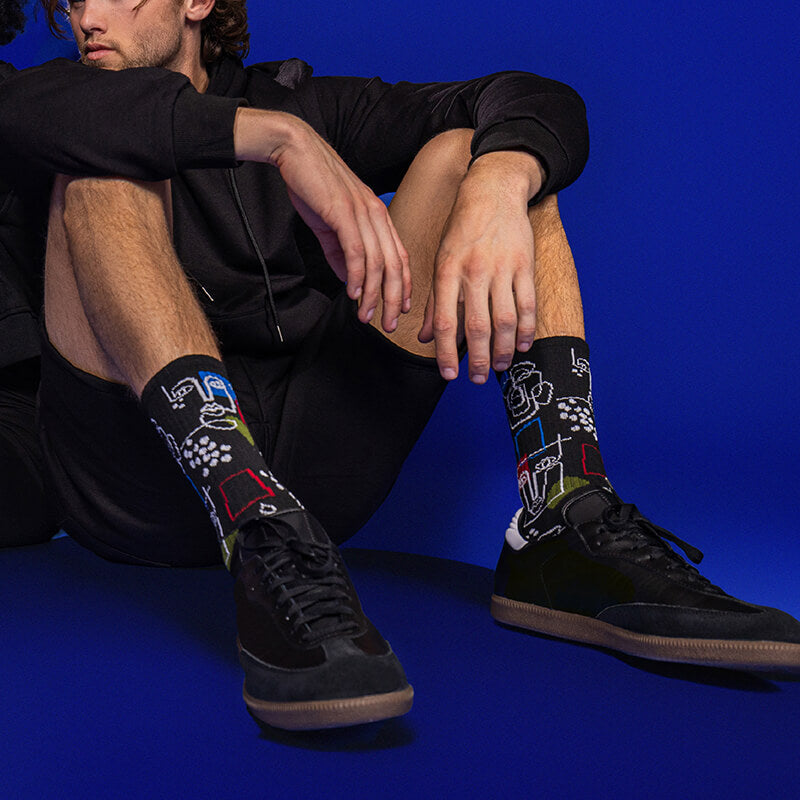 Person wearing black socks with colorful designs on a blue background