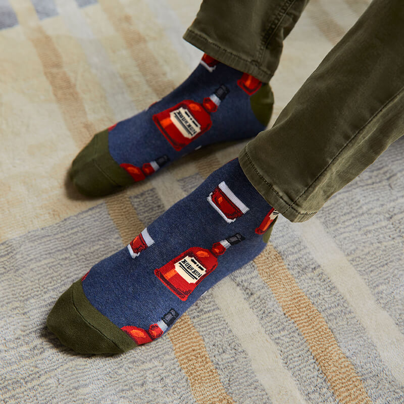 Person wearing socks with bottle designs on a carpeted floor