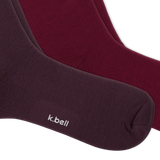 Two pairs of crew socks from k.bell, fanned out on a white background, with three tiers of ruffled colors from dark plum to burgundy, maroon, and dusty pink.