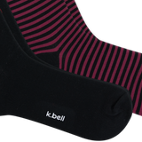 Close-up of two pairs of socks, with one sock in solid black showing the white 'k.bell' logo and the other showing a black and dark pink striped pattern.