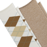 Two pairs of knit socks arranged diagonally on a white background. The front pair is off-white with an argyle pattern in brown, tan, and light blue, and the second pair is a solid heathered beige.