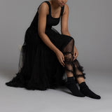 Person wearing a black dress and black  laced ankle socks on a gray background thumbnail
