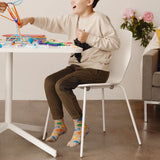 Child sitting at a table playing with colorful toys in a room with a couch and flowers. thumbnail