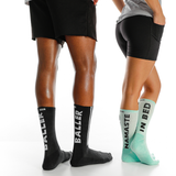 Two pairs of socks with text on them worn by people, one black with 'BALLER' and one green with 'NAMASTE IN BED'. thumbnail