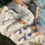 Two people sitting on a blanket wearing matching floral outfits and socks. thumbnail