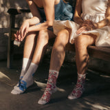 Two people sitting on a bench wearing floral socks. thumbnail