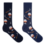 A pair of men's navy blue crew socks with a cognac and cigars theme, featuring illustrations of a cognac glass, a cigar, and other smoking accessories.